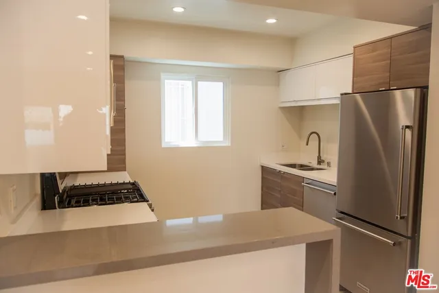 a kitchen with granite countertop a refrigerator and a stove top oven