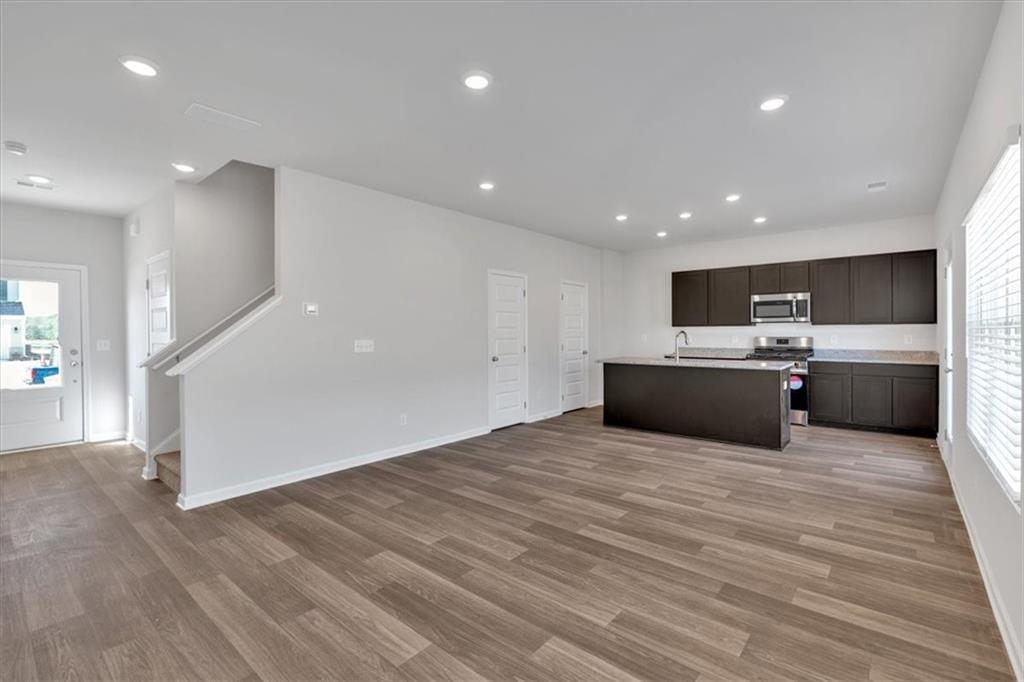 117 Lavender Circle Calhoun, GA 30701 - Photo 6 of 22 a large white kitchen with kitchen island a sink wooden floor and stainless steel appliances