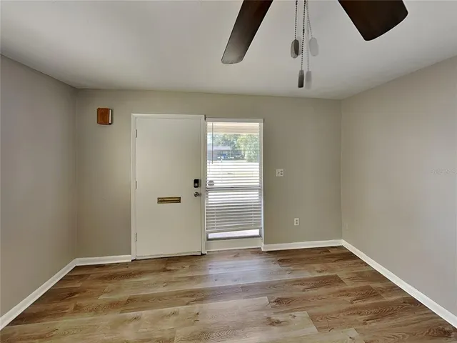 an empty room with wooden floor cabinet and windows