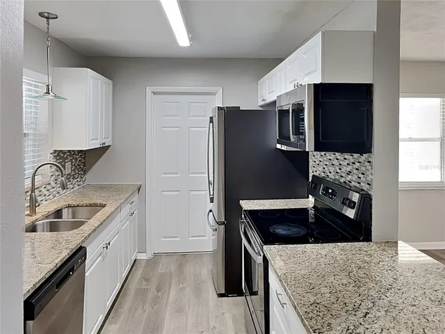 a kitchen with granite countertop stainless steel appliances a sink stove and refrigerator