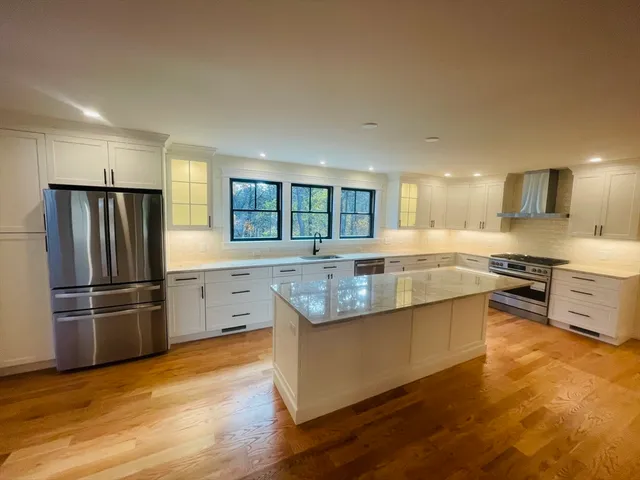 a large kitchen with granite countertop a large counter top stainless steel appliances and cabinets