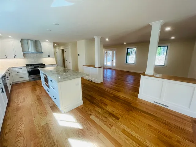a large kitchen with stainless steel appliances granite countertop a lot of counter space and wooden floor
