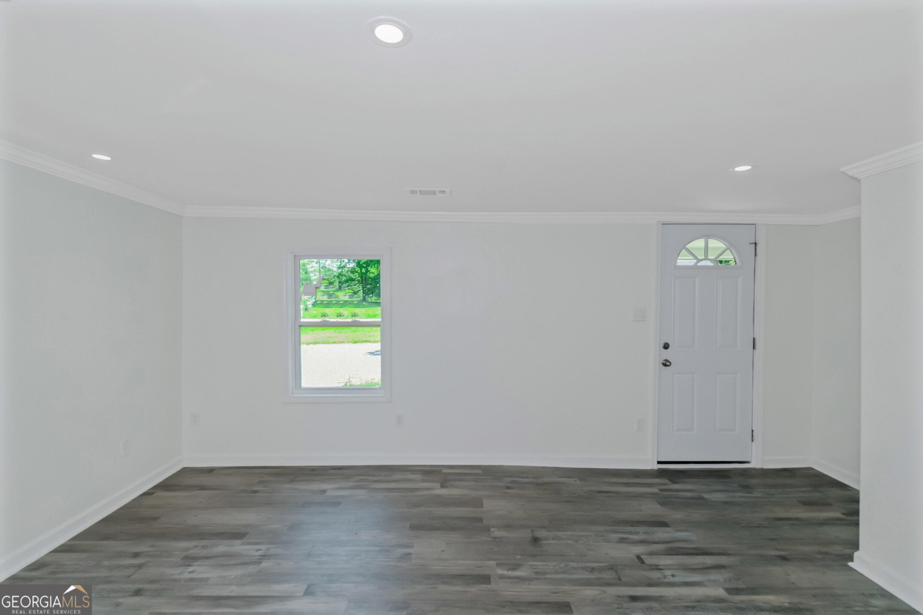 204 Mill Street Barnesville, GA 30204 - Photo 6 of 35 a view of an empty room with wooden floor and a window