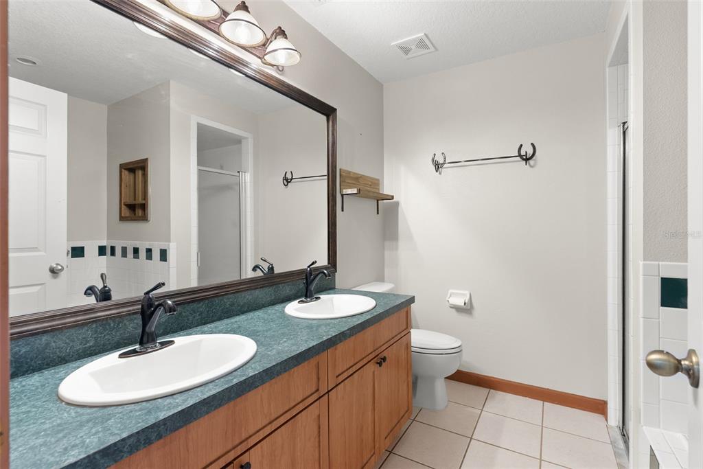 17620 North Poyner Road Polk City, FL 33868 - Photo 26 of 46 a bathroom with a granite countertop sink a toilet and a mirror