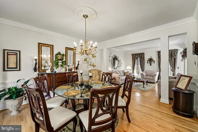 a view of a dining room and livingroom with furniture wooden floor a chandelier