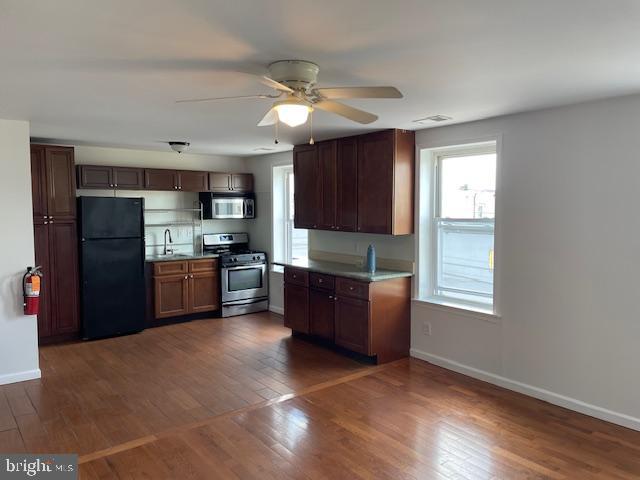 a large kitchen with stainless steel appliances granite countertop a refrigerator a sink dishwasher a stove with wooden cabinets and floor