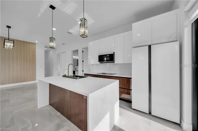 a kitchen with kitchen island a sink stainless steel appliances and chandelier