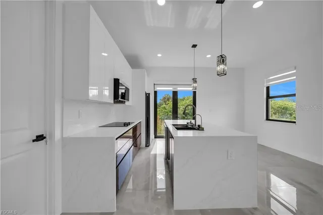 a kitchen with stainless steel appliances granite countertop a refrigerator a sink dishwasher a stove and a dining table with wooden floor