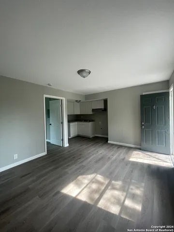 a view of empty room with wooden floor and window