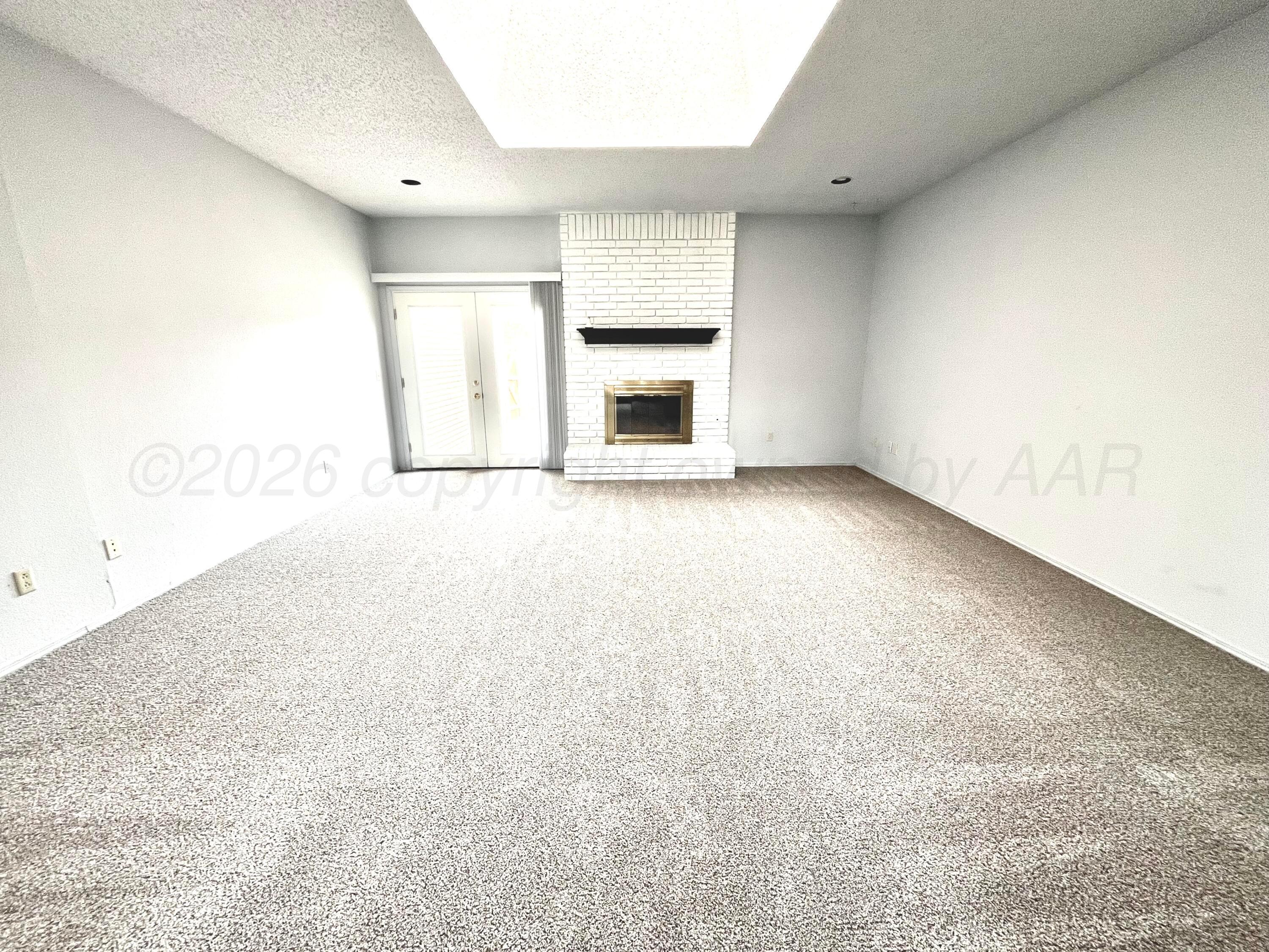 7628 Catskill Avenue Amarillo, TX 79121 - Photo 2 of 16 an empty room with a fireplace and windows