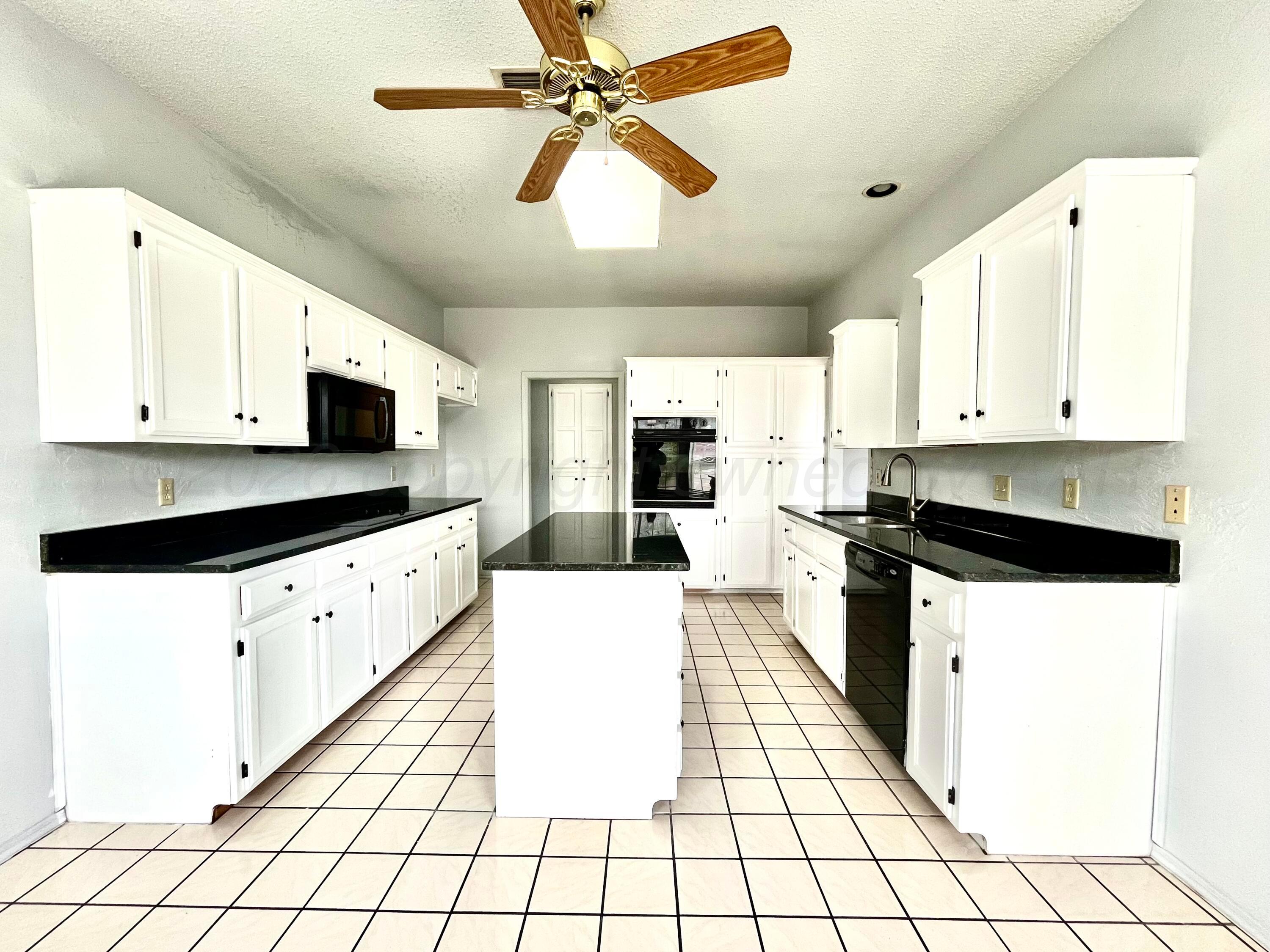 7628 Catskill Avenue Amarillo, TX 79121 - Photo 6 of 16 a kitchen with stainless steel appliances kitchen island granite countertop a sink a stove top oven and white cabinets