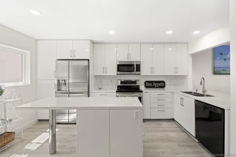 a kitchen with stainless steel appliances kitchen island granite countertop a refrigerator and a sink