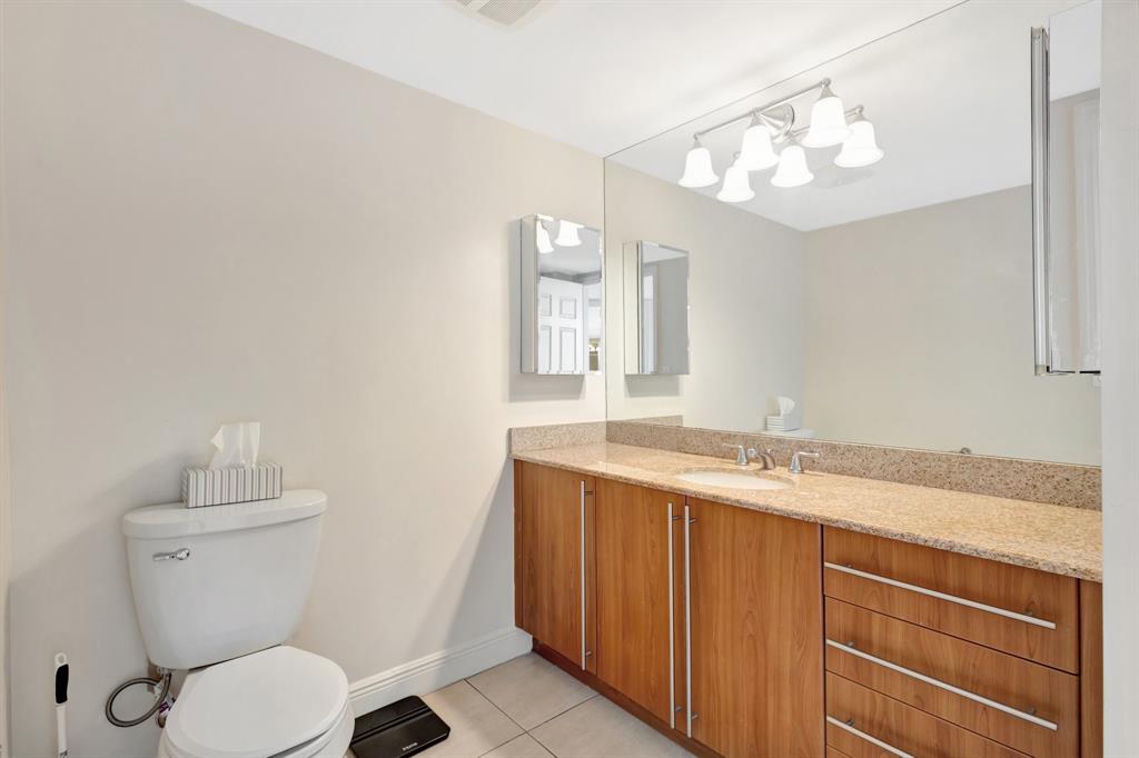 610 Clematis Street, Unit 412 West Palm Beach, FL 33401 - Photo 18 of 52 a bathroom with a granite countertop toilet sink and mirror