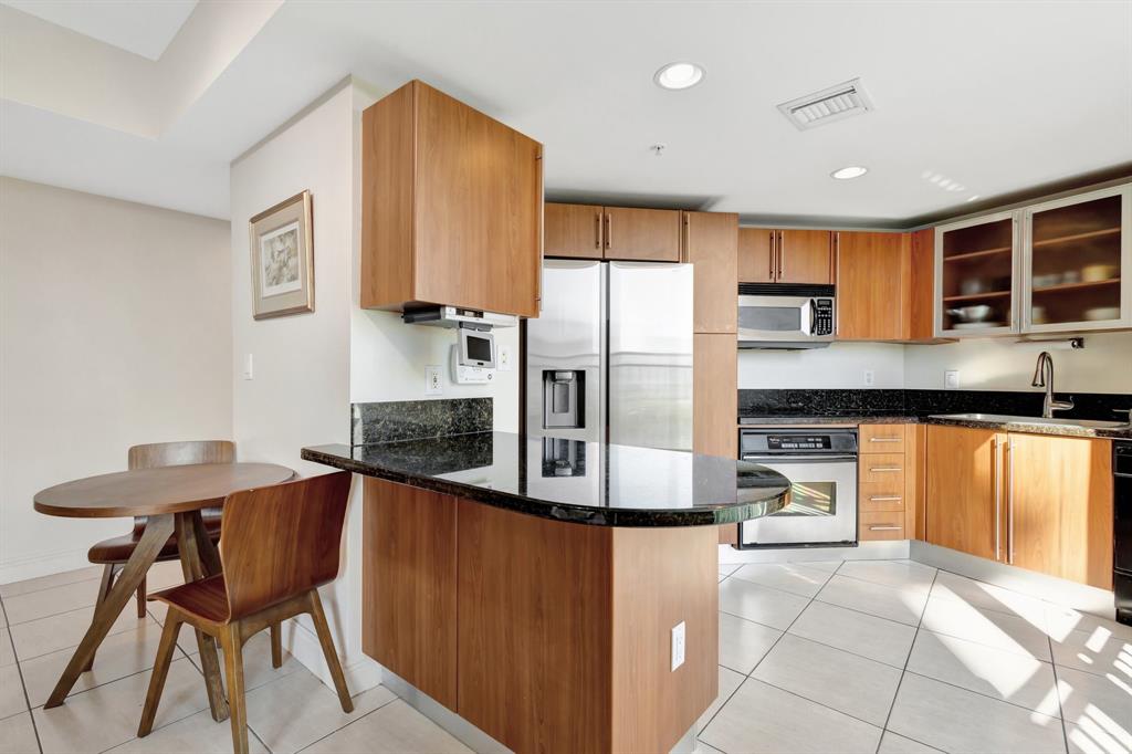 610 Clematis Street, Unit 412 West Palm Beach, FL 33401 - Photo 8 of 52 a kitchen with stainless steel appliances granite countertop a refrigerator a stove a sink a dining table and chairs with wooden floor