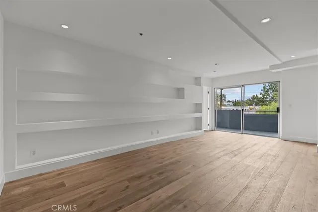 a view of empty room with wooden floor and windows