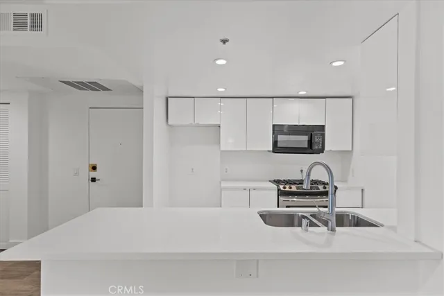 a kitchen with a sink a stove and white cabinets