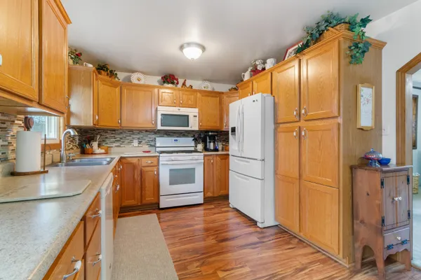 a kitchen with stainless steel appliances granite countertop a refrigerator a stove and a sink with wooden floor