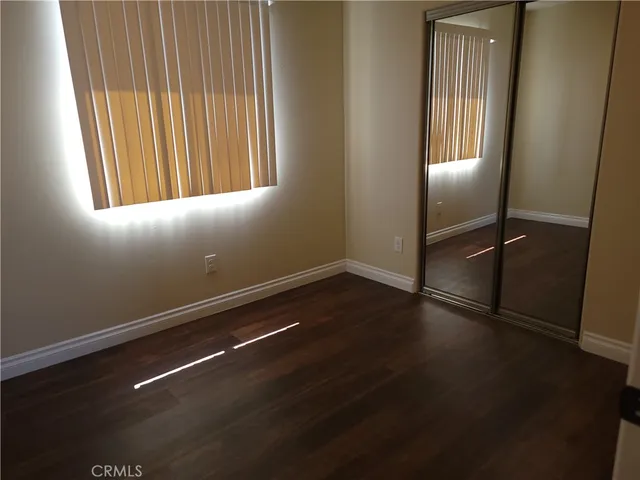 an empty room with wooden floor and windows with curtains
