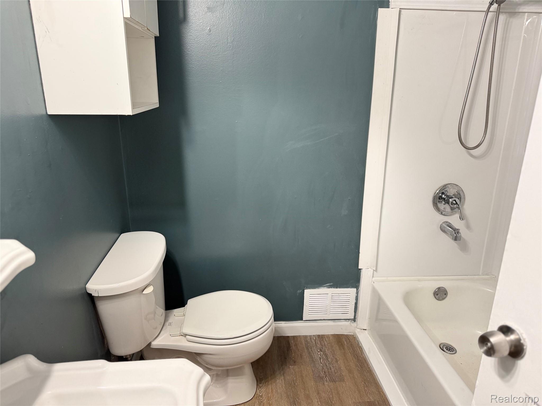 5347 Mapletree Drive Flint, MI 48532 - Photo 9 of 10 Bathroom featuring wood-finish flooring and a white bathtub with a chrome shower fixture