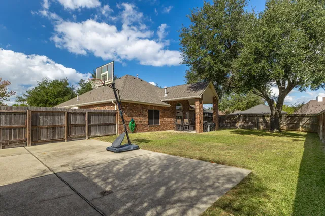 a view of a house with backyard and trees