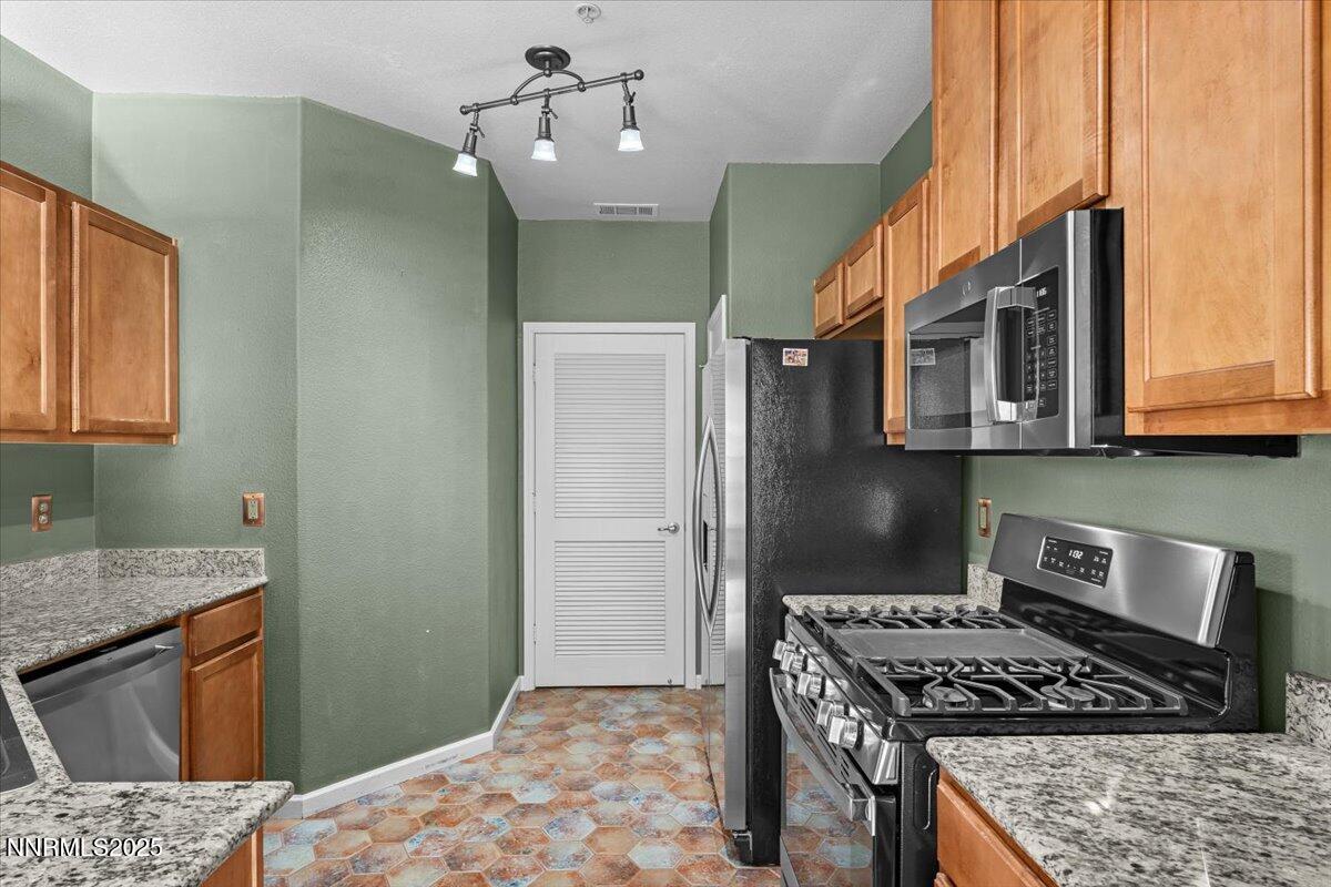 9050 Double R Boulevard, Unit 821 Reno, NV 89521 - Photo 7 of 20 a kitchen with stainless steel appliances granite countertop a stove a sink dishwasher and refrigerator with wooden floor