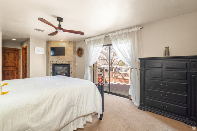 892 Cambridge Drive St. George, UT 84770 - Photo 48 of 65 Room featuring a corner fireplace with stone surround, a ceiling fan, and sliding glass doors opening to a wood-finish deck