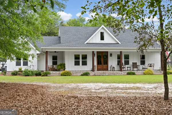 a front view of a house with garden and trees