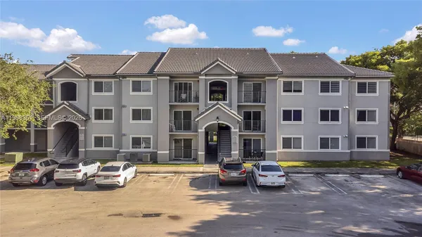 a front view of a building with cars parked
