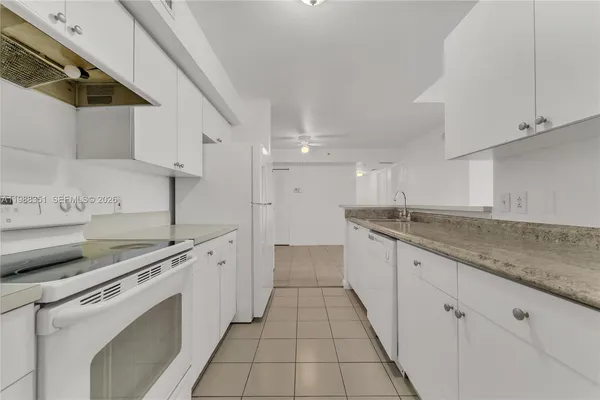 a kitchen with white cabinets sink and appliances