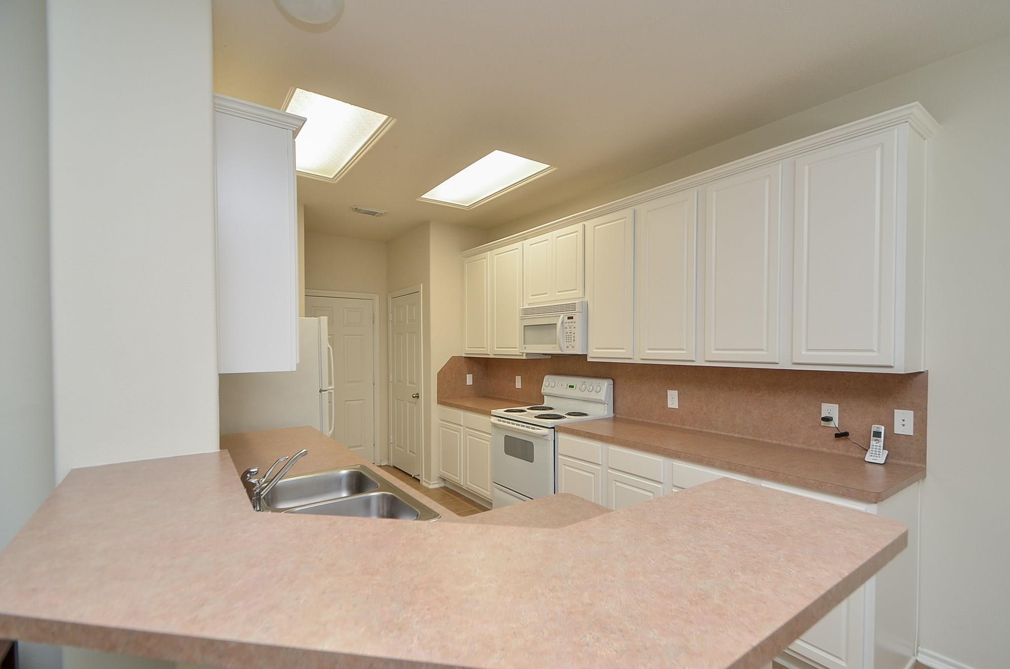 46 East Stedhill Loop Conroe, TX 77384 - Photo 12 of 32 a kitchen with stainless steel appliances granite countertop a sink refrigerator and cabinets