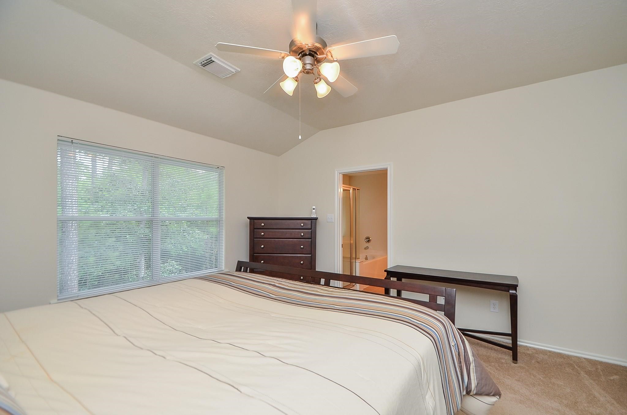 46 East Stedhill Loop Conroe, TX 77384 - Photo 16 of 32 a bedroom with a large bed and a chandelier