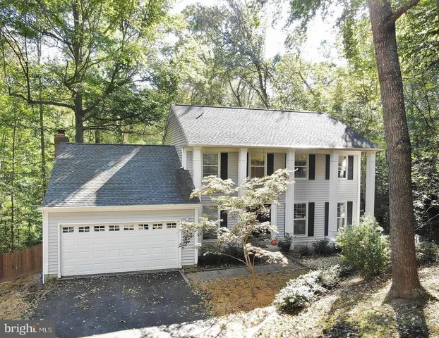 a view of a white house with a large tree and wooden fence