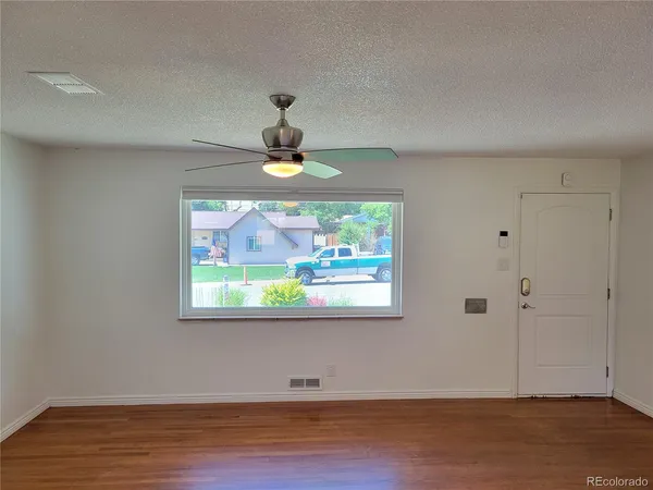 a view of an empty room with wooden floor and window