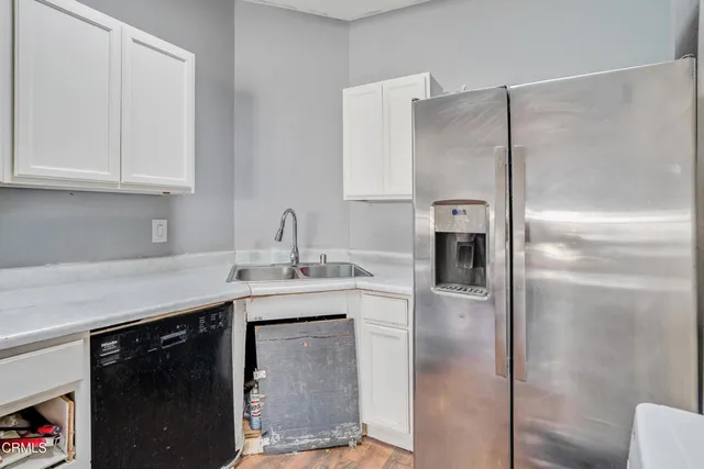 a kitchen with stainless steel appliances granite countertop a refrigerator a sink and white cabinets