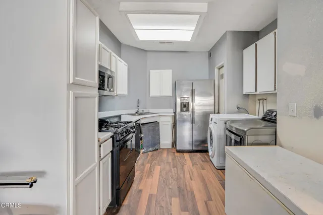 a kitchen with stainless steel appliances a refrigerator a sink a stove top oven and wooden floor