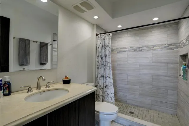 a bathroom with a granite countertop shower sink vanity mirror and toilet