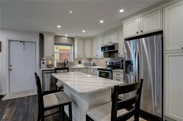 a kitchen with kitchen island a refrigerator stove microwave and cabinets