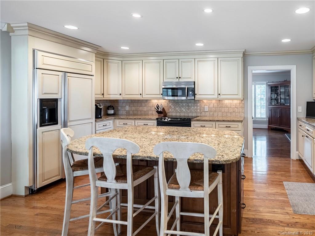 3200 Wickersham Road Charlotte, NC 28211 - Photo 6 of 40 a large kitchen with kitchen island granite countertop a stove a table and chairs with wooden floor