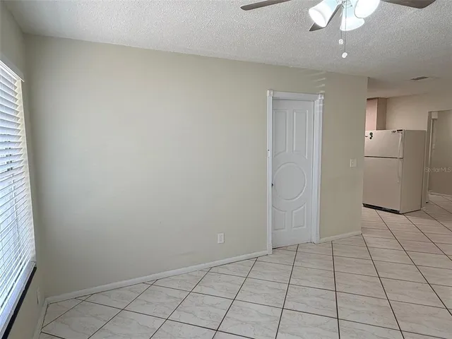 a view of an empty room with window and chandelier fan