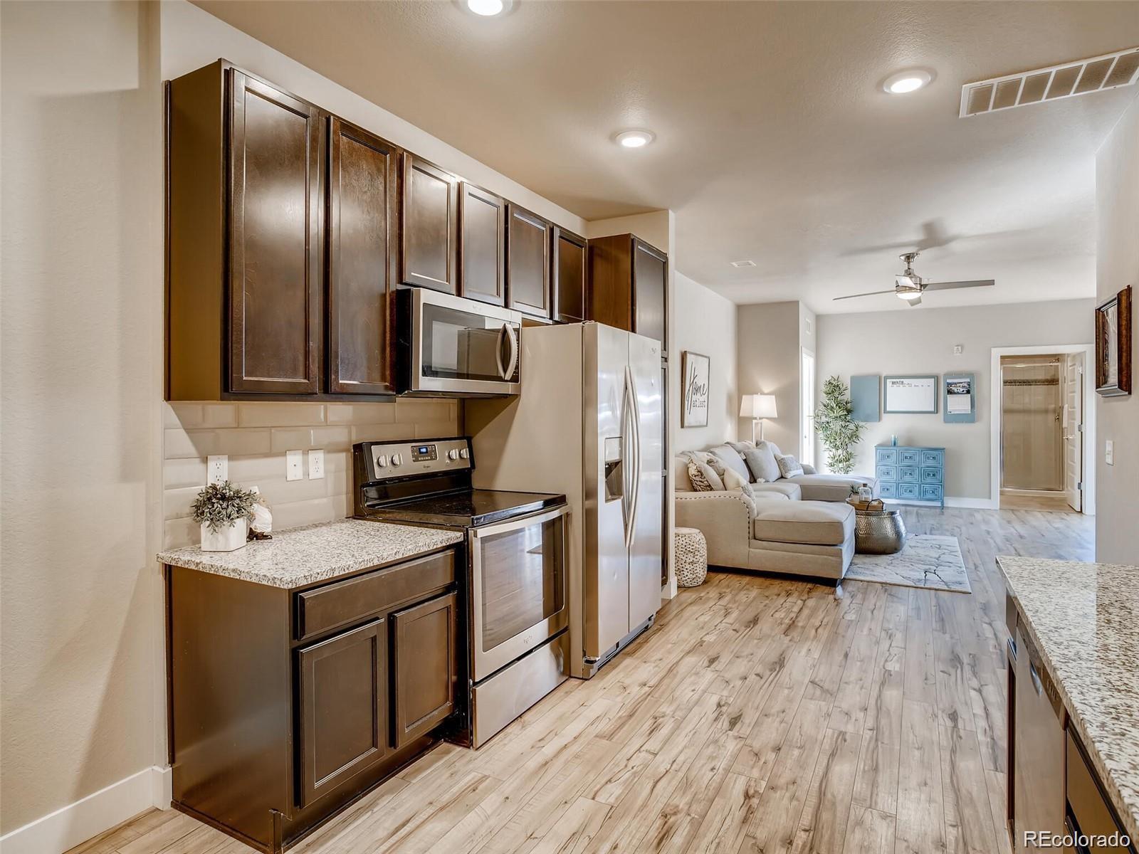 15274 West 64th Lane, Unit 107 Arvada, CO 80007 - Photo 12 of 24 a kitchen with a refrigerator sink and wooden cabinets