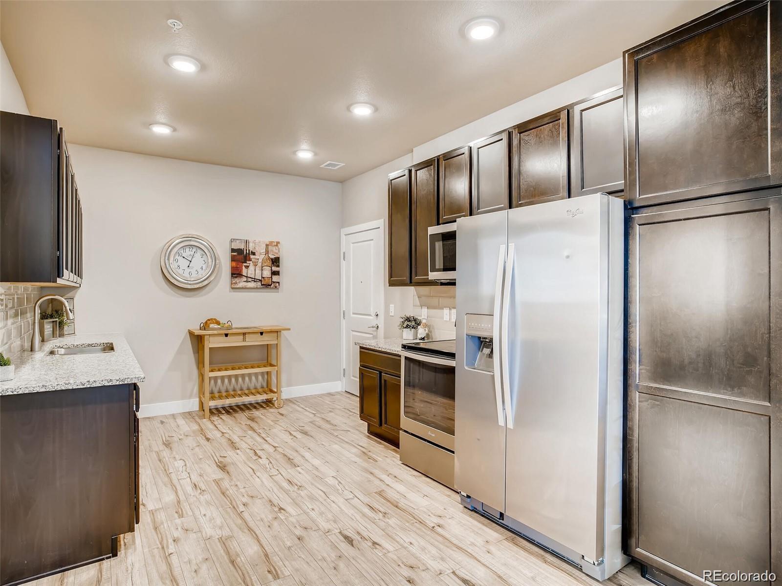 15274 West 64th Lane, Unit 107 Arvada, CO 80007 - Photo 13 of 24 a kitchen with stainless steel appliances granite countertop a refrigerator stove microwave and sink