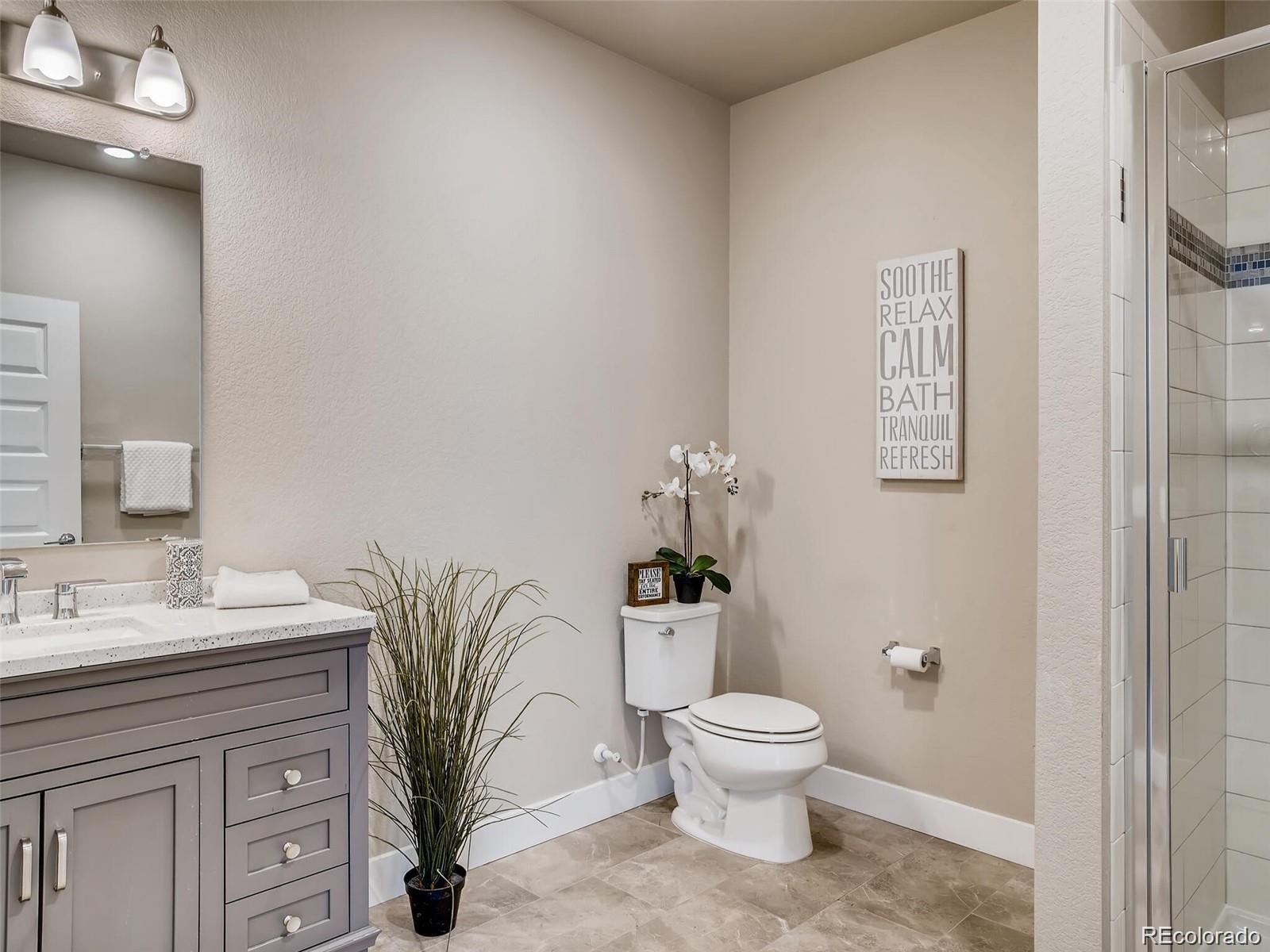 15274 West 64th Lane, Unit 107 Arvada, CO 80007 - Photo 14 of 24 a spacious bathroom with a toilet sink and mirror