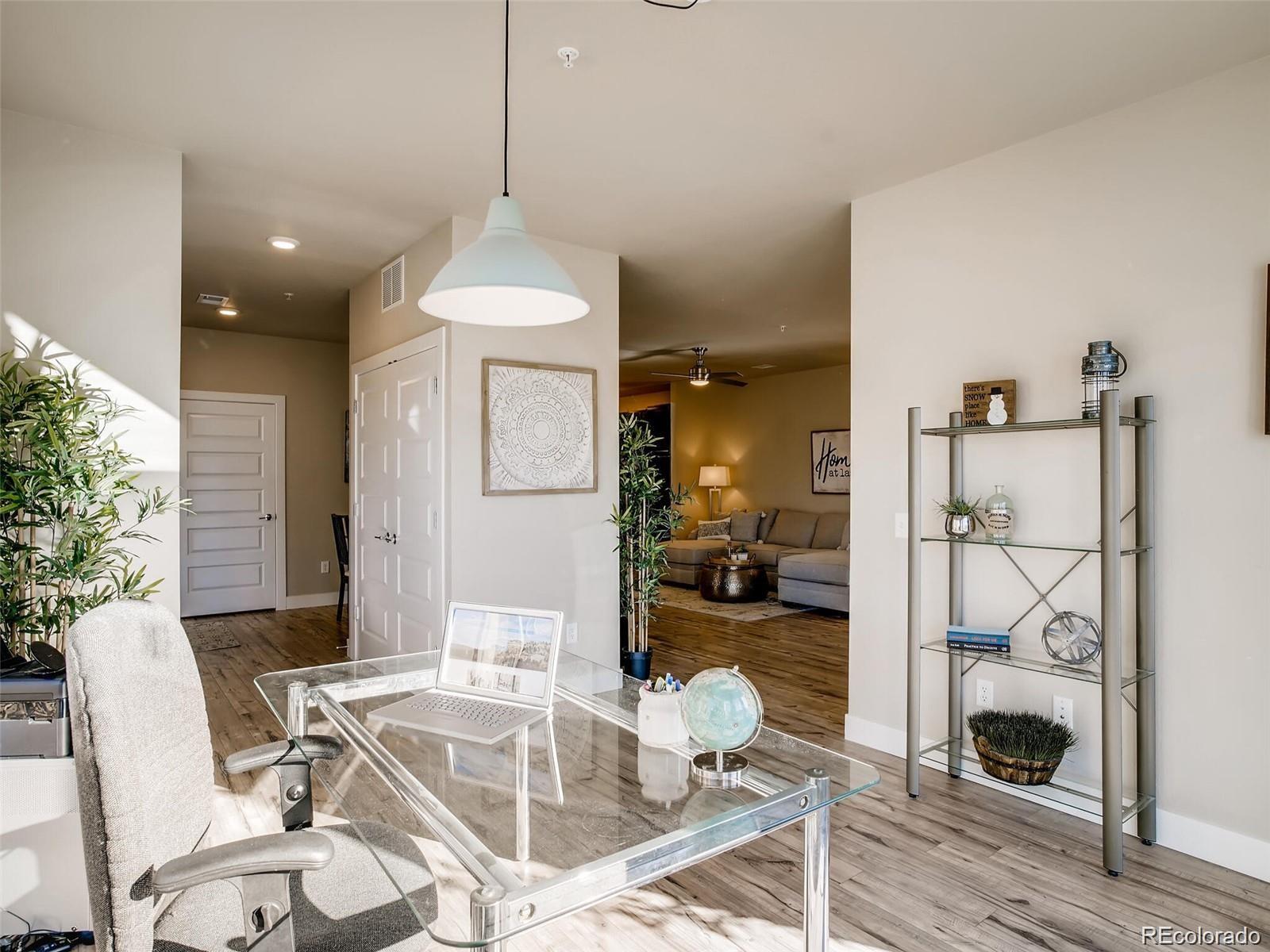15274 West 64th Lane, Unit 107 Arvada, CO 80007 - Photo 3 of 24 a dining room with wooden floor and a chandelier