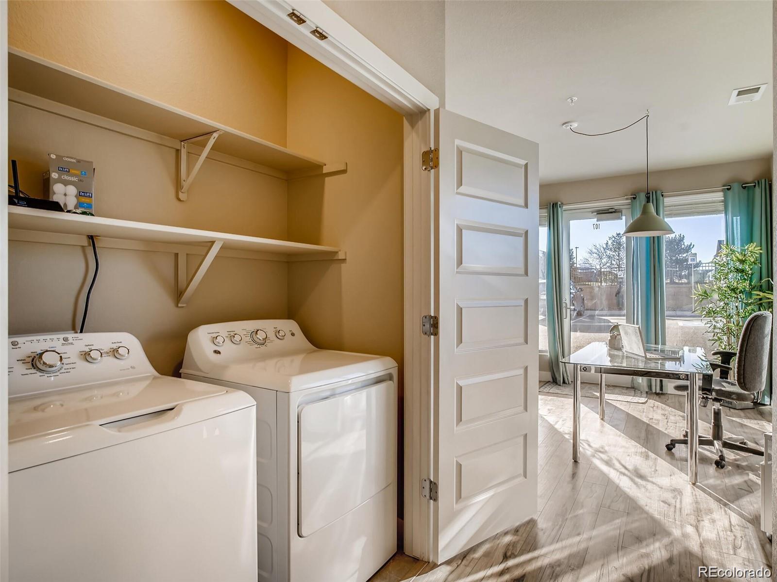 15274 West 64th Lane, Unit 107 Arvada, CO 80007 - Photo 7 of 24 a view of washer and dryer with kitchen in the background