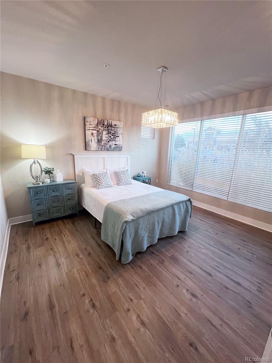 15274 West 64th Lane, Unit 107 Arvada, CO 80007 - Photo 8 of 24 a bedroom with a bed and wooden floor