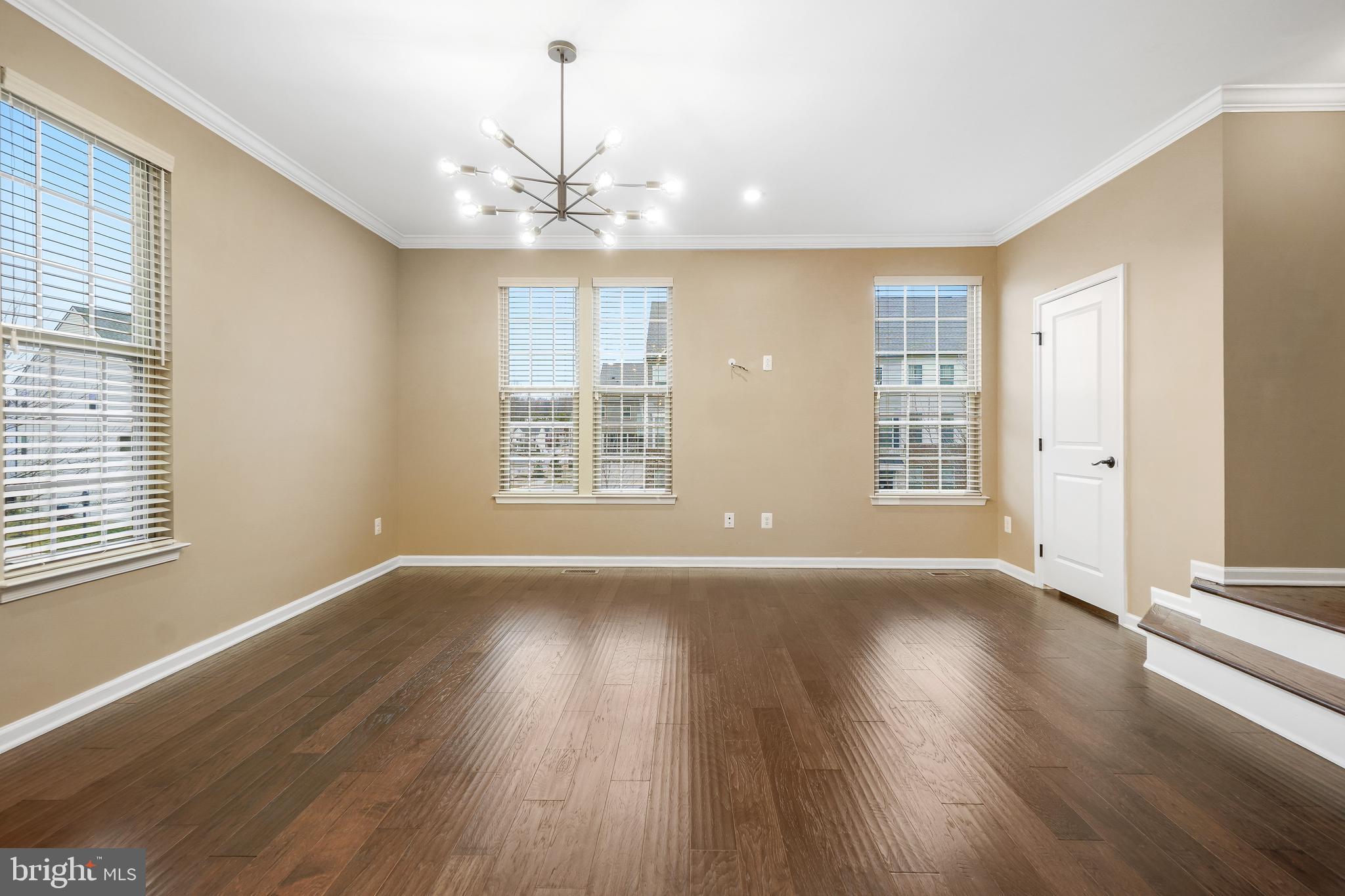 2011 Serviceberry Road Dumfries, VA 22026 - Photo 6 of 25 an empty room with wooden floor chandelier and windows