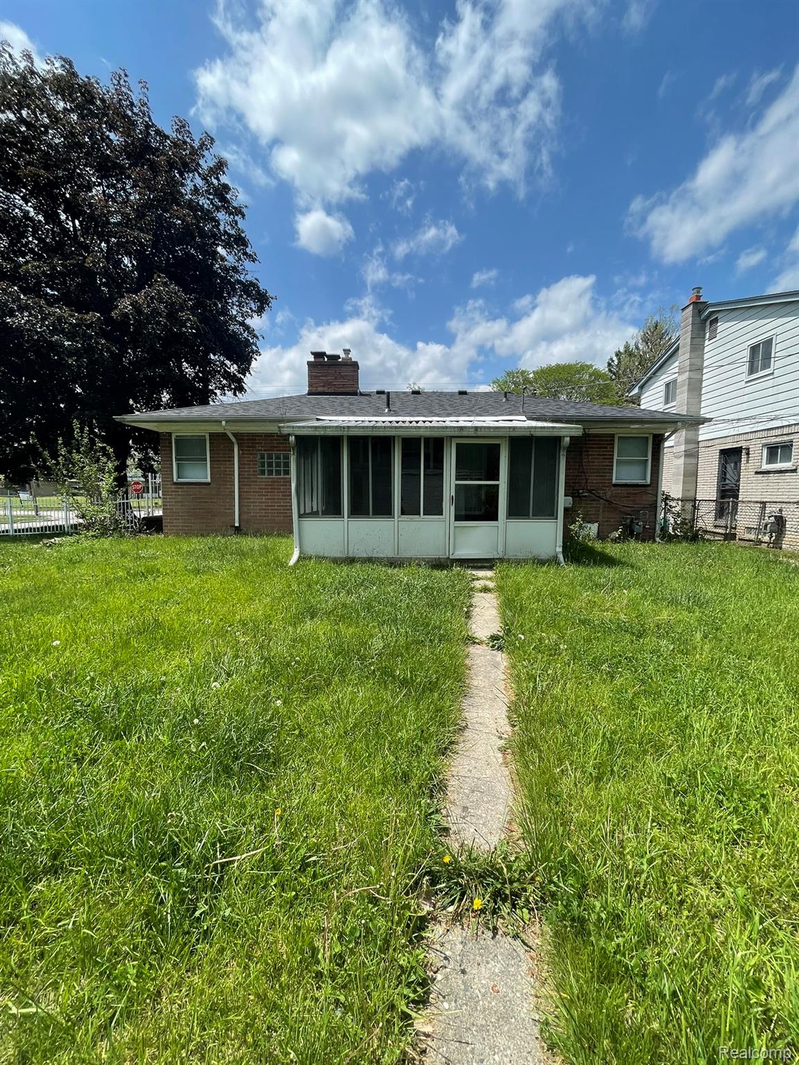 19800 Berg Road Detroit, MI 48219 - Photo 13 of 13 Brick exterior home featuring a screened-in porch with a white frame, a concrete walkway, and a large backyard area