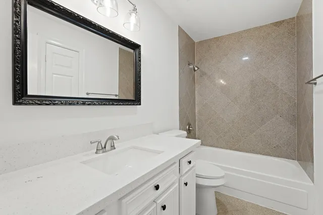 a bathroom with a sink vanity granite toilet tub and shower