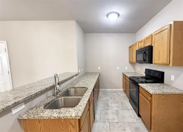 a kitchen with kitchen island granite countertop a sink and a stove top oven with wooden floor