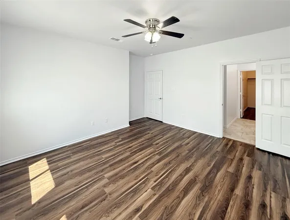 a view of a room with wooden floor and a ceiling fan